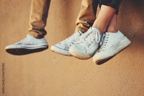 Shoes, building a friends relax outside in summer for bonding, friendship and calm carefree fun. People, fashion and footwear freedom, weekend and bond or peaceful relationship in summer by a wall