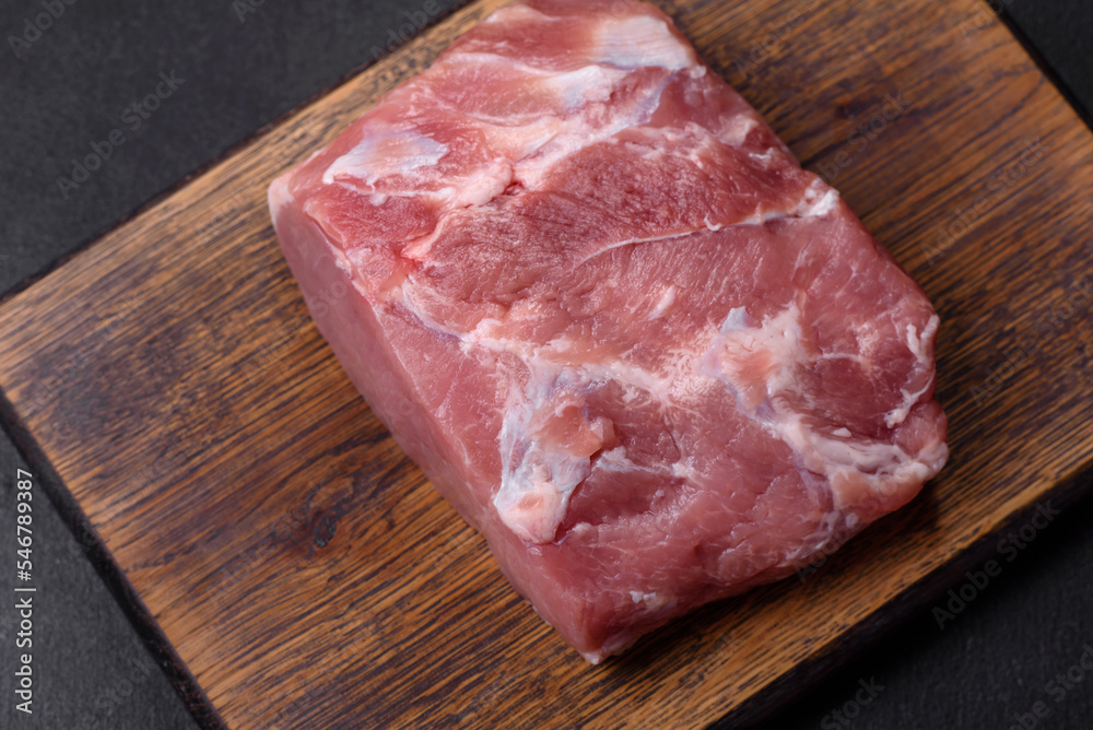 Fresh piece of raw pork with spices, salt and herbs on a wooden cutting board Fresh piece of raw pork with spices, salt and herbs on a wooden cutting board