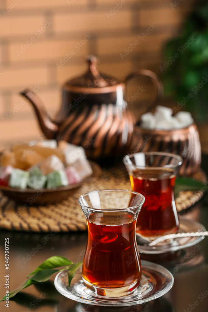 Saucer with glass of Turkish tea and leaf on table in room, closeup Saucer with glass of Turkish tea and leaf on table in room, closeup
