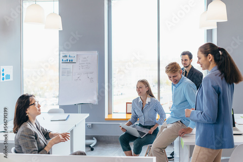 Business woman making a presentation to her colleagues during meeting or in-house training, explaining business plans to her employees