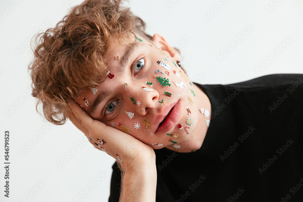 © BONNINSTUDIO/Stocksy - Bored young male with Christmas stickers on face