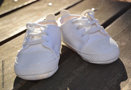 White little sneakers for baby on the wooden floor