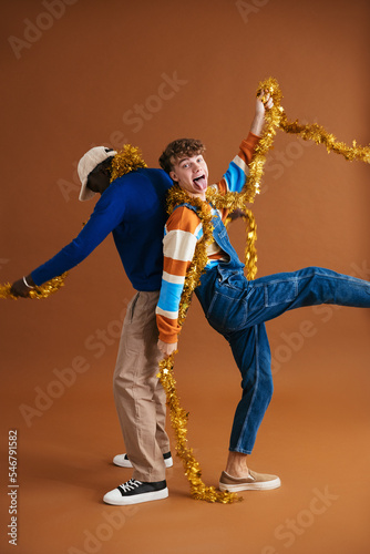 Playful men with gold tinsel in studio