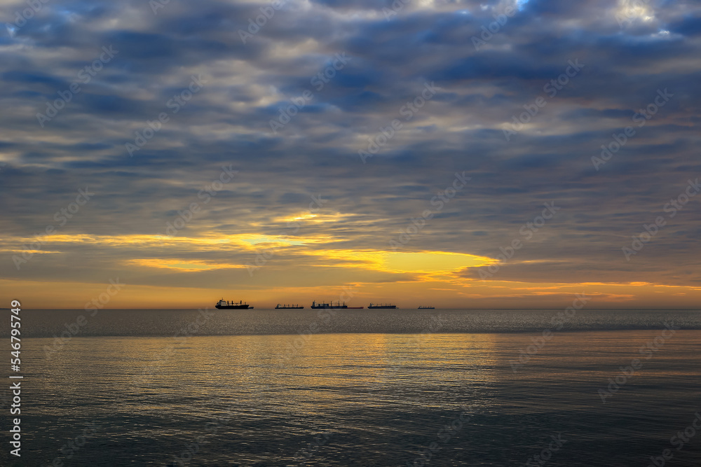 Sunrise over the Baltic Sea with a view of ships sailing on the horizon line in Gdynia, Poland