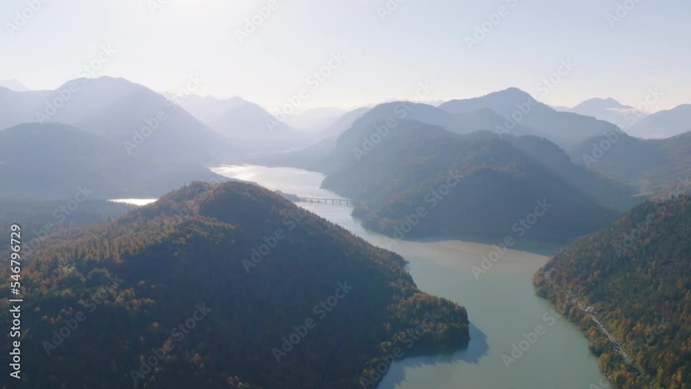 Sunrise shining over Isar river aerial orbiting view across Faller-klamm-brücke hazy autumnal alpine mountain range