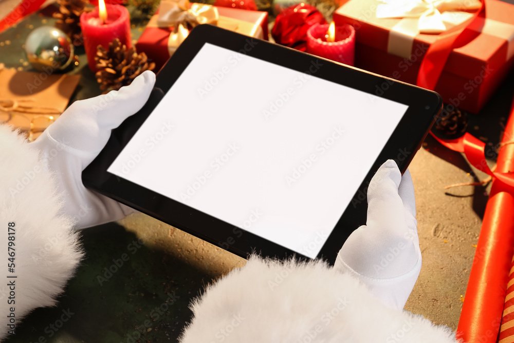 Santa Claus with tablet computer on green table, closeup Santa Claus with tablet computer on green table, closeup