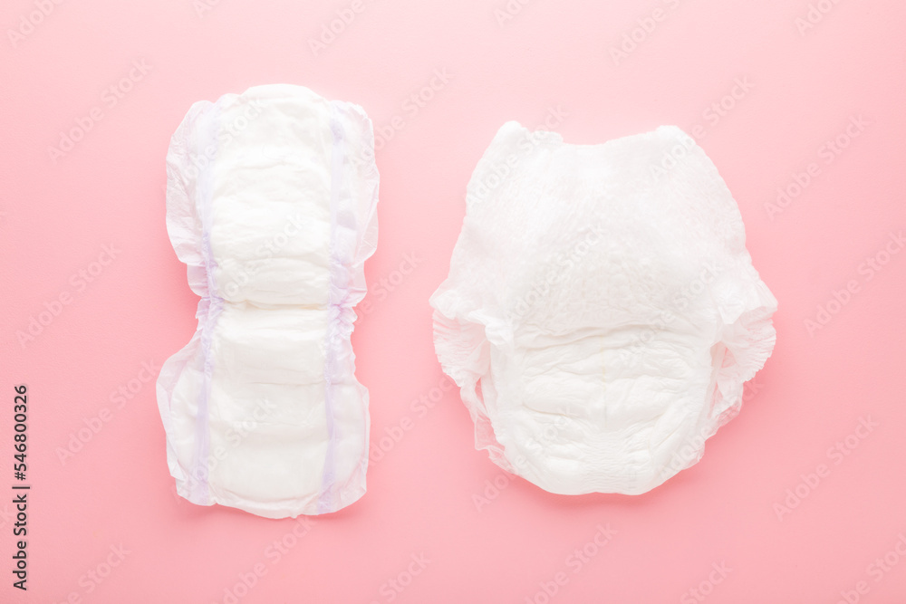 White big size sanitary towel and diaper pant on light pink table ...