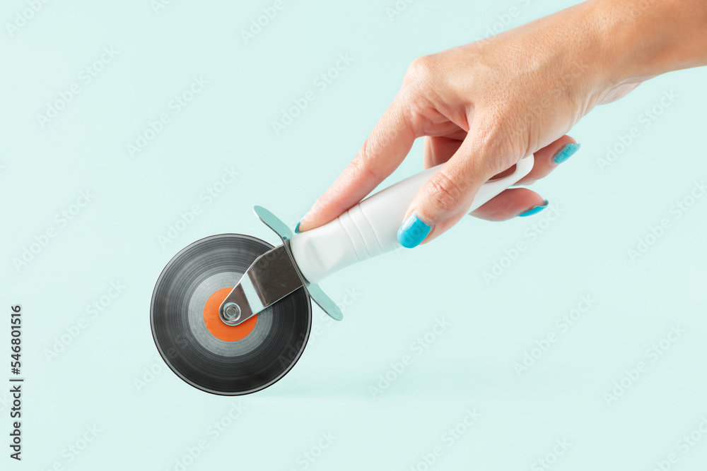 Woman’s hand holding pizza cutter with vinyl record on isolated pastel background. Minimal abstract creative retro musical concept of vintage music concert, festival or dj party. Invitation card. Woman’s hand holding pizza cutter with vinyl record on isolated pastel background. Minimal abstract creative retro musical concept of vintage music concert, festival or dj party. Invitation card.