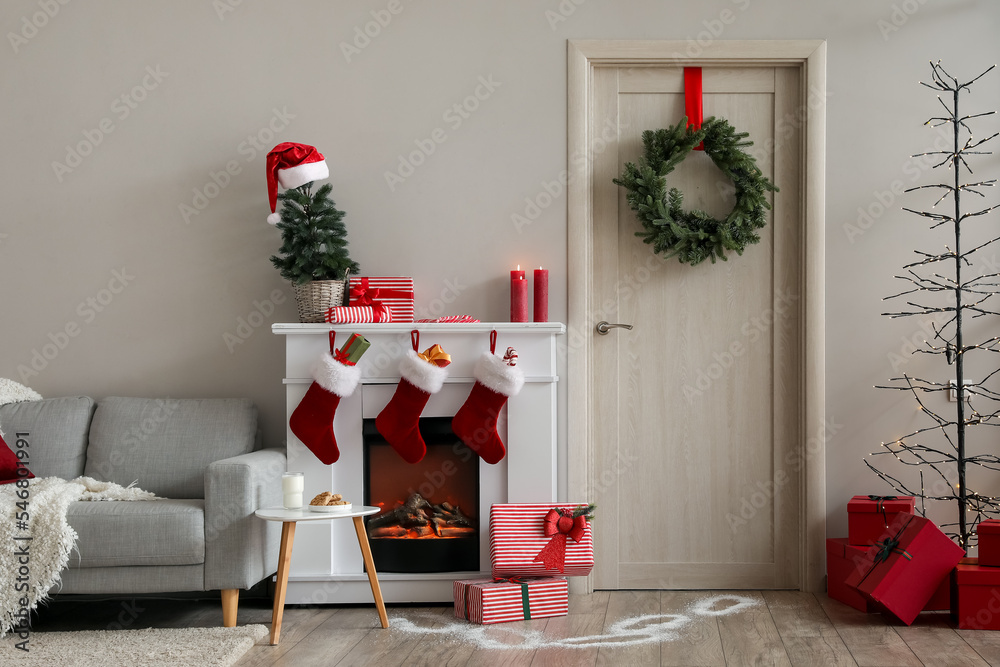 Fototapeta premium Interior of living room with wooden door, fireplace and Christmas decor