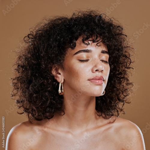 Woman, beauty and freckles, curly hair and facial treatment, makeup and body care aesthetics, shine or glow on studio background. Young model, melasma face and natural cosmetics, skincare or wellness photo