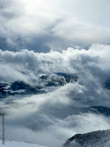 Misty day in the mountains with snowfall clouds rolling across snowy landscape © helivideo