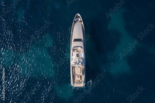 A large Mega yacht for charter travel is anchored on clear water, top view. Innovative large yachts on the water vice air.