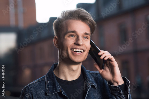 Caucasian blond guy in a denim jacket talking on a mobile phone or smartphone.