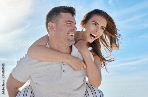 Love, beach and piggy back couple smile with blue sky on romantic summer holiday at ocean. Romance, man and woman have fun at sea for honeymoon, vacation time for happy couple together in Australia. #546807969