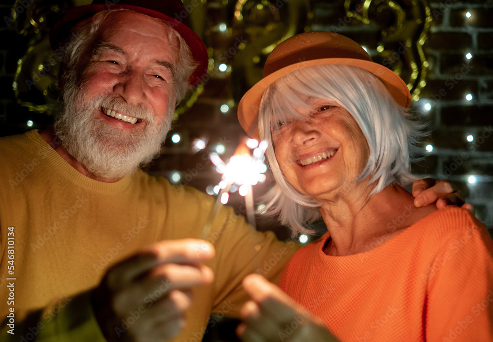 Cheerful caucasian senior couple holding sparklers celebrating new year. Happy lifestyle for mature retirees, party lights