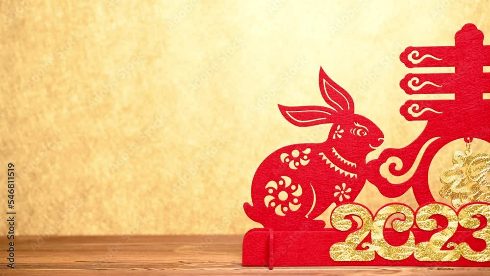 pan view Chinese New Year of Rabbit mascot paper cut with red pockets on gold background at horizontal composition the Chinese words means fortune and springtime no logo no trademark