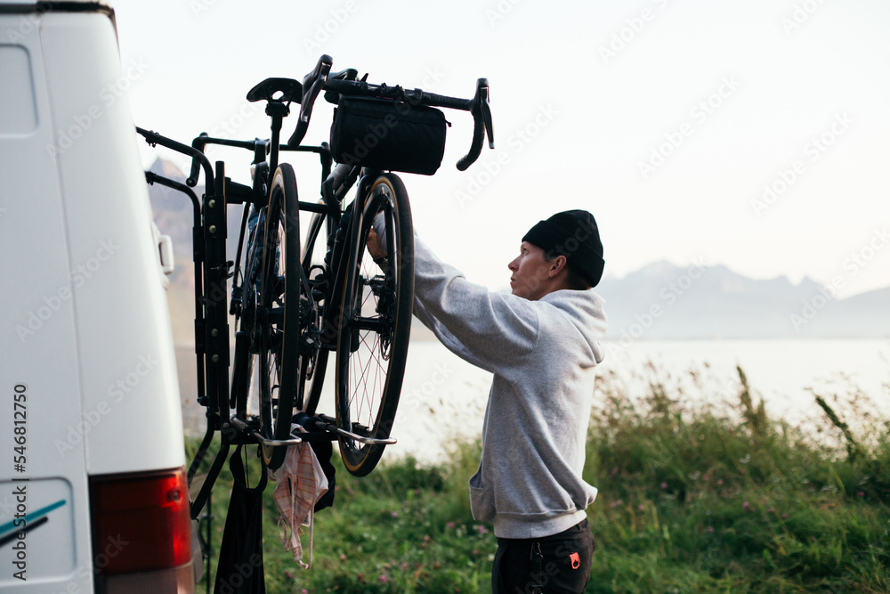 Foto de Man attach two bikes to bike rack on back of camper van. Cycling adventure travel