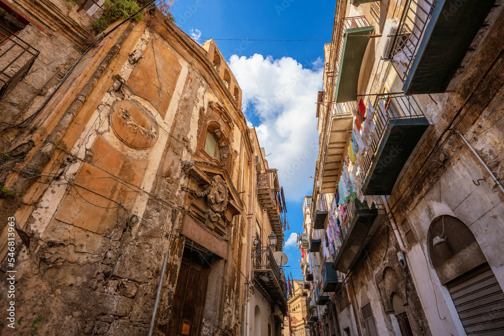 Aged buildings in the historic center of Palermo with clothes hanging on the balconies
