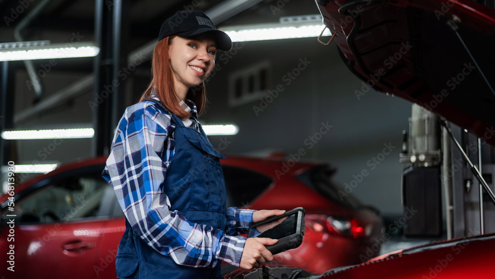 Caucasian female auto mechanic uses a special computer to diagnose faults. 