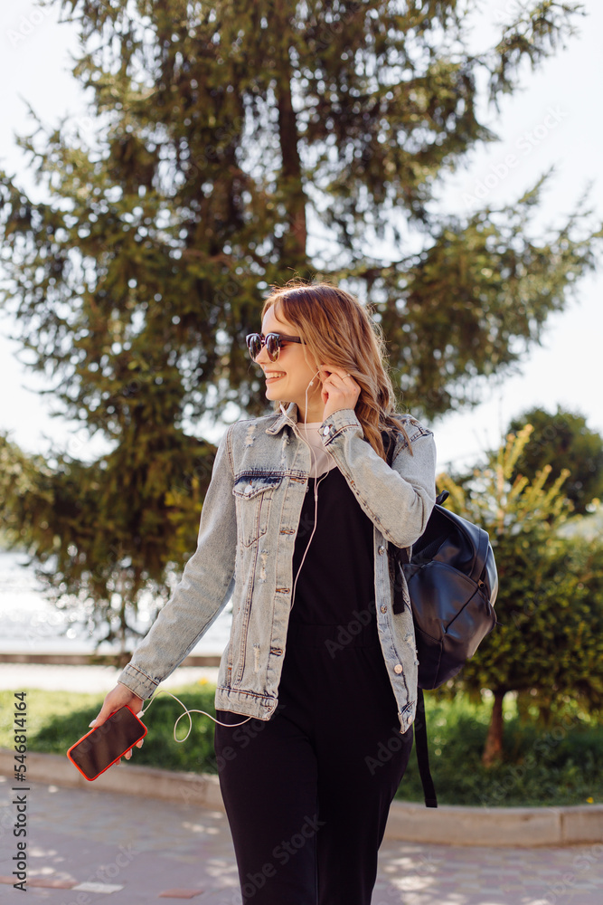 Photo of a positive cheerful teenage girl spends time in the park and using mobile phone. Photo of a positive cheerful teenage girl spends time in the park and using mobile phone.