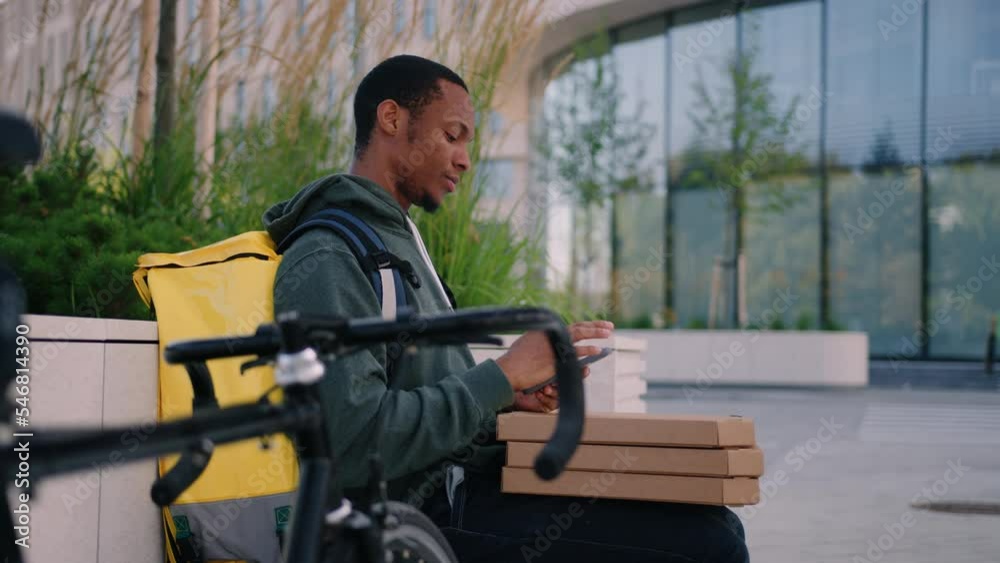 Pizza delivery to offices. A bike courier with a mobile phone is waiting for a customer outside Pizza delivery to offices. A bike courier with a mobile phone is waiting for a customer outside