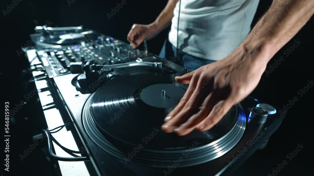 Hip hop dj scratching vinyl record on turntables in night club. Professional disc jockey plays music