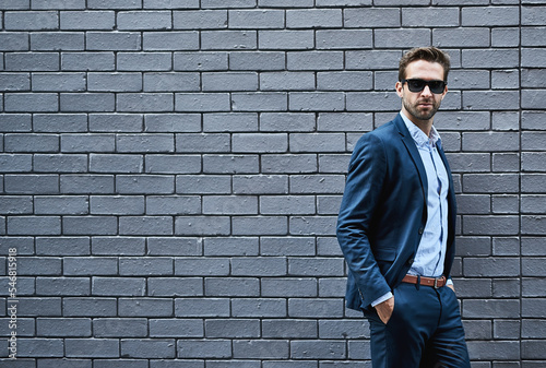 Business man, fashion and sunglasses on ceo, boss or executive against wall background in city for success, wealth and goals. Professional urban male outdoor in formal, luxury or designer clothes