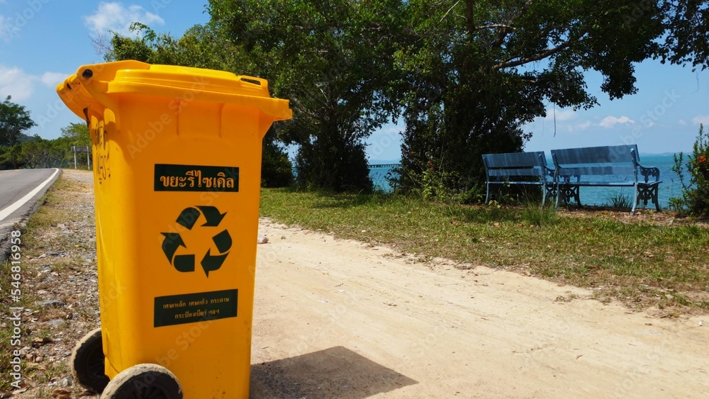 Plastic bin yellow for Garbage Waste at asphalt road in asian tropical coast. Thailand, Koh Chang. Garbage waste bin trash, Recycle waste bin, Plastic Bin for Yellow Garbage. Recycle symbol icon logo