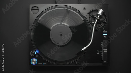 DJ turntable playing vinyl record with music in flat lay 4K video clip. Retro disc jockey player filmed directly from above on a black background.  photo