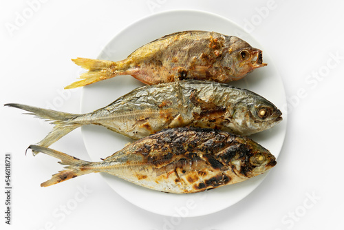 Canvas Print Top down view or flatlay closeup served Grilled burn three fish in a white round plate on isolated clean white background