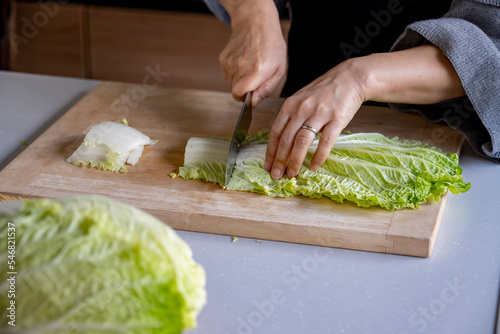 Woman cutting Chinese cabbage on cutting board.
Cooking Chinese cabbage image.
