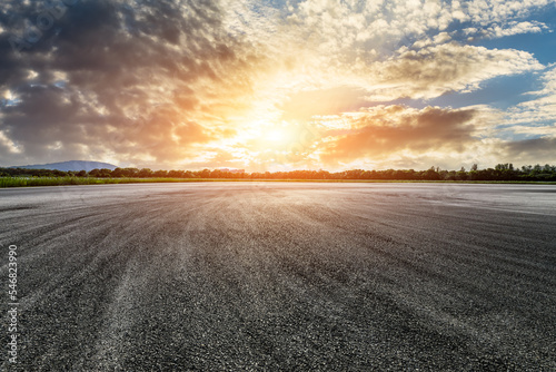 Empty asphalt road and green forest with sky clouds at sunset © ABCDstock