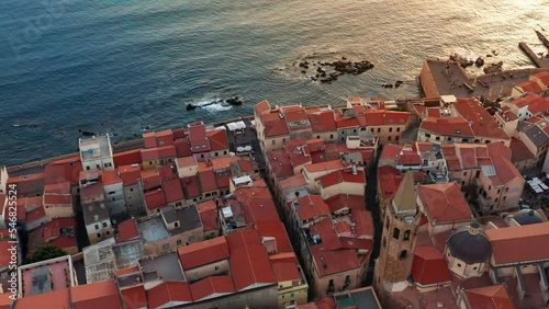 Drone view circling over the old town of Alghero at susent.
Golden hour, warm cinematic colors. photo