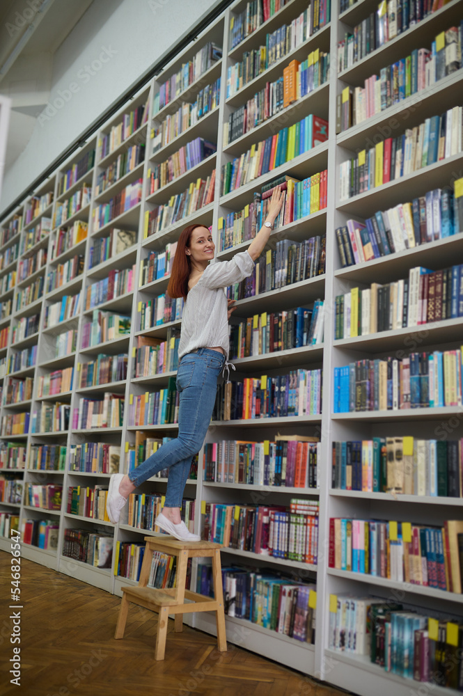 Young librarian searching for a book on bookshelves Young librarian searching for a book on bookshelves