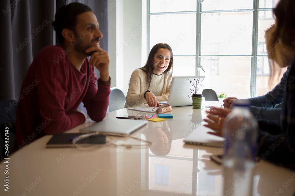 Coworkers sitting at meeting table in office Coworkers sitting at meeting table in office