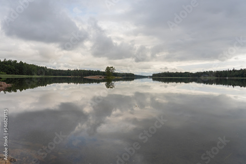 Beautiful view of the quiet lake reflecting the gray sky on a cloudy day outside. Landscape. Scandinavia.