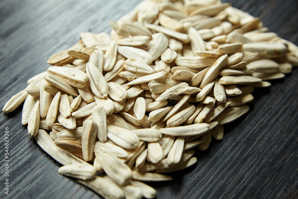 White sunflower seeds on table. Heap of Salted roasted sunflower seeds with white shell on wooden background White sunflower seeds on table. Heap of Salted roasted sunflower seeds with white shell on wooden background