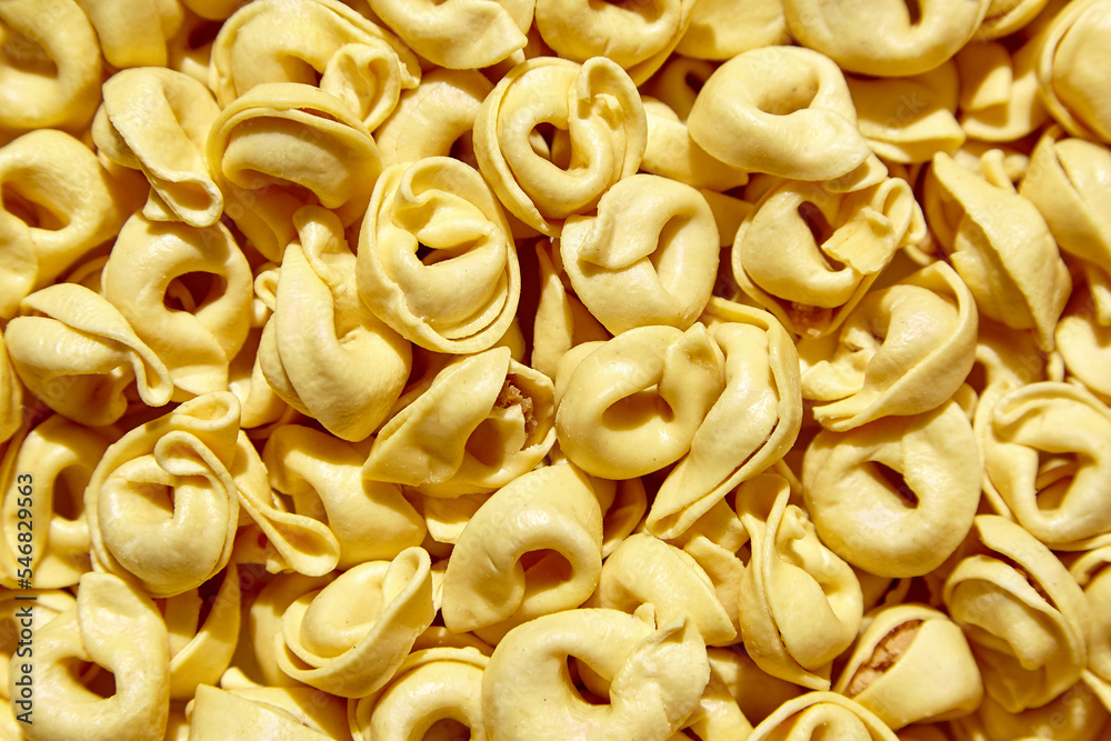 Tortellini pasta with prosciutto, food background, top view. Italian stuffed pasta