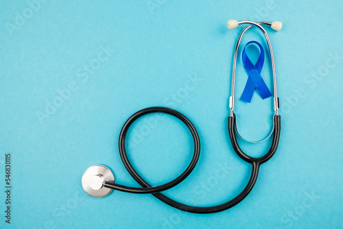 Top view photo of stethoscope and blue ribbon symbol of prostate cancer awareness on isolated pastel blue background photo