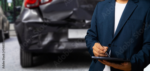Side view of insurance officer writing on tablet while insurance agent examining black car after accident. © JC_STOCKER