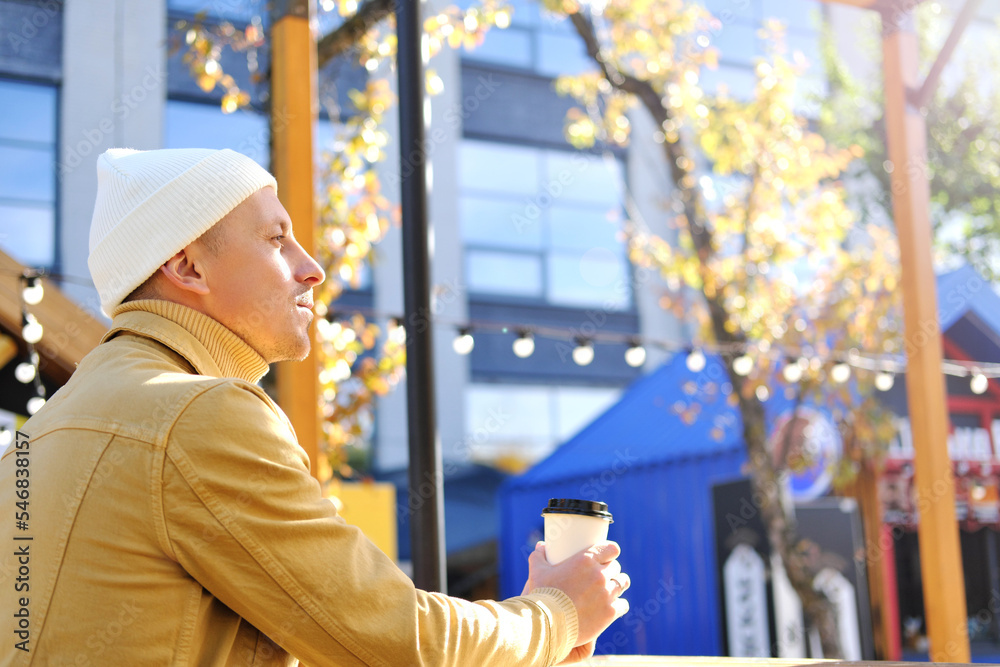 A young man in a yellow jacket drinks coffee, enjoys the good weather and thinks about something A young man in a yellow jacket drinks coffee, enjoys the good weather and thinks about something