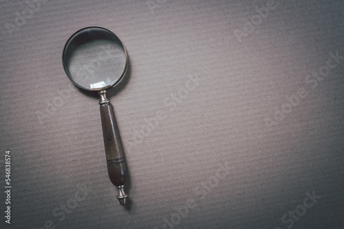 Magnifying glass on dark gray paper background