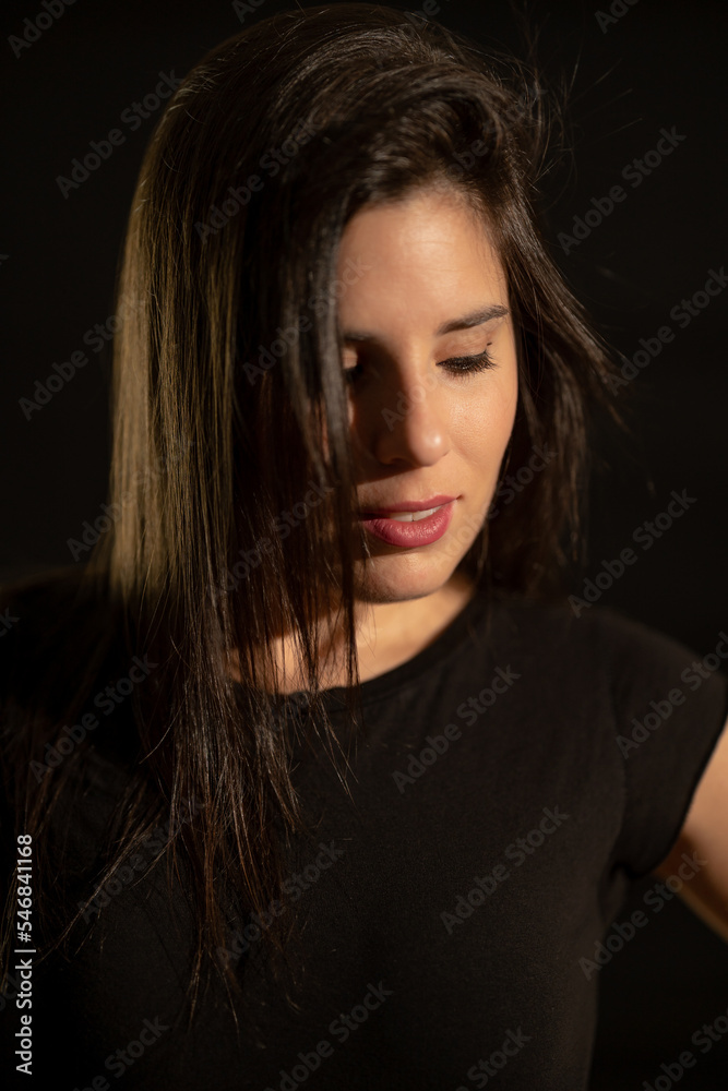 Portrait of a young woman on a black background with a soft, warm and cozy light. Portrait of a young woman on a black background with a soft, warm and cozy light.