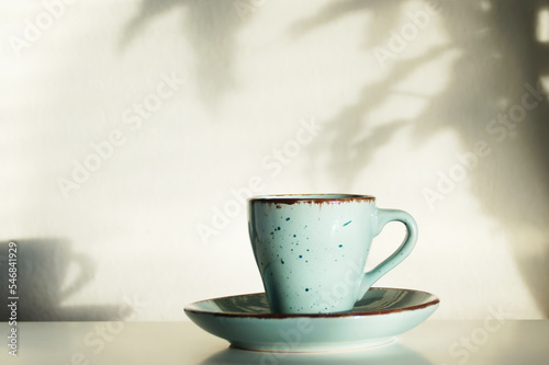 Ceramic handmade mug on the background of a wall with shadows,