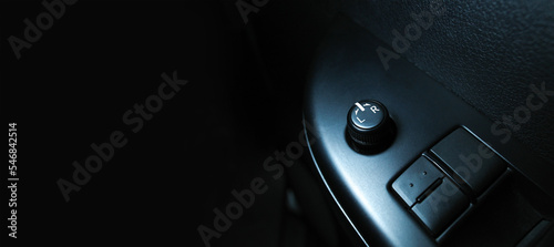 Car wing mirror adjustment switch on armrest panel, panoramic banner with copy space on black background