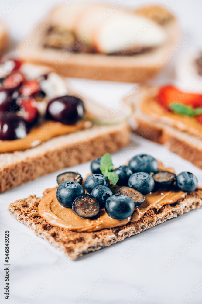 Various kind of open sandwiches with berries and fruits. Made from bread, such as wholegrain, rice crakers, crispbreads and different nut butter, such as peanut, crunchy cashew and almond butter Various kind of open sandwiches with berries and fruits. Made from bread, such as wholegrain, rice crakers, crispbreads and different nut butter, such as peanut, crunchy cashew and almond butter