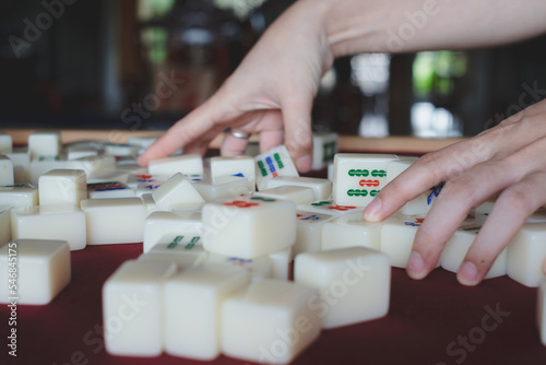 Hands arranging, playing Mahjong game. Concept of chinese leisure games traditional, family activity, Hongkong board game, chinese new year fmily time entertainment. Lucky game.