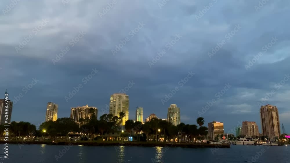 Coastal Panoramic View of St-Petersburg City Florida in Cloudy Evening Across Tampa Bay, Sailing on Water Along Coast and Marina, illuminated Buildings and Cityscape in Horizon Coastal Panoramic View of St-Petersburg City Florida in Cloudy Evening Across Tampa Bay, Sailing on Water Along Coast and Marina, illuminated Buildings and Cityscape in Horizon