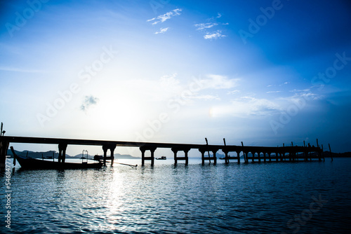 silhouette of boat and bridge at sunlight in sea before sun set