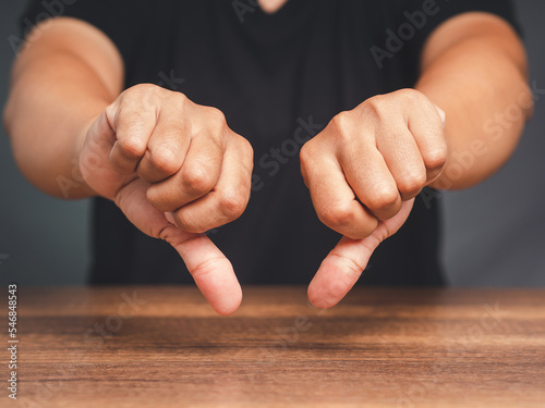 Close-up of young man's hands showing a thumbs down for dislike service